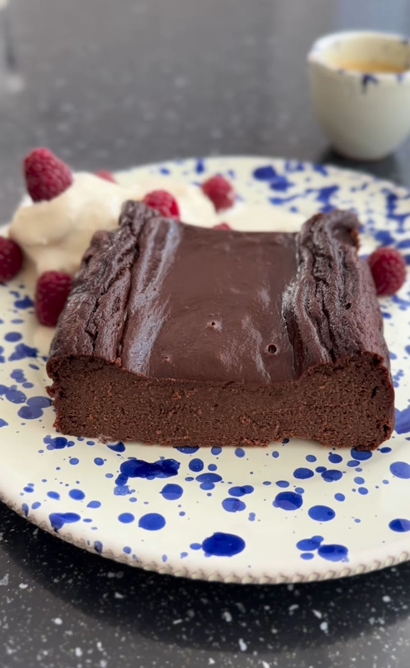 Appetizing homemade chocolate cake decorated with cream placed on table near candles and plates